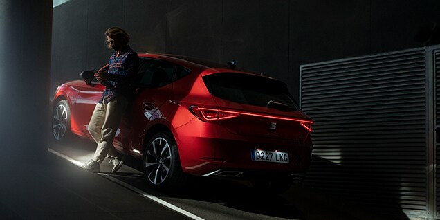 hombre cargando un seat león phev bajo iluminación ambiental, se destacan las subvenciones 